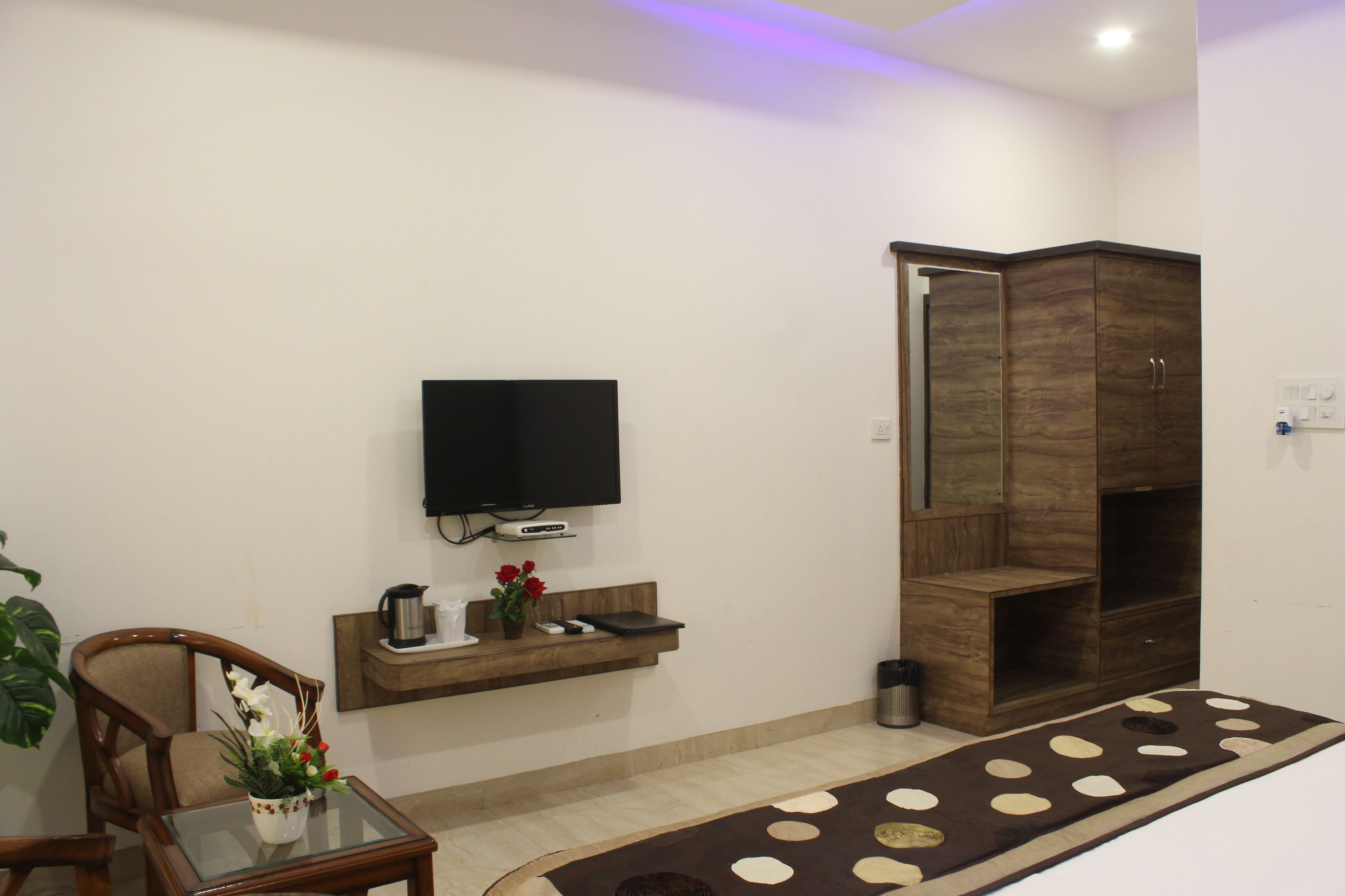 A modern living room with a flat-screen TV, wooden furniture, a coffee table with a vase, and a patterned rug.