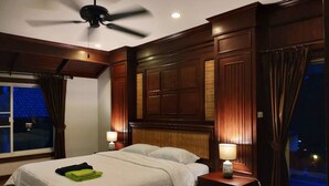A hotel room with a bed, two bedside tables, a ceiling fan, and a window with curtains. - Momoka Luxury Villa (San Sai)
