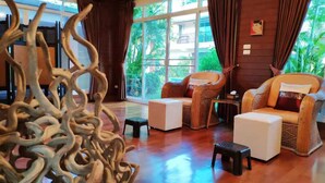 A spacious room with a large window, wicker furniture, and a decorative sculpture. - Momoka Luxury Villa (San Sai)
