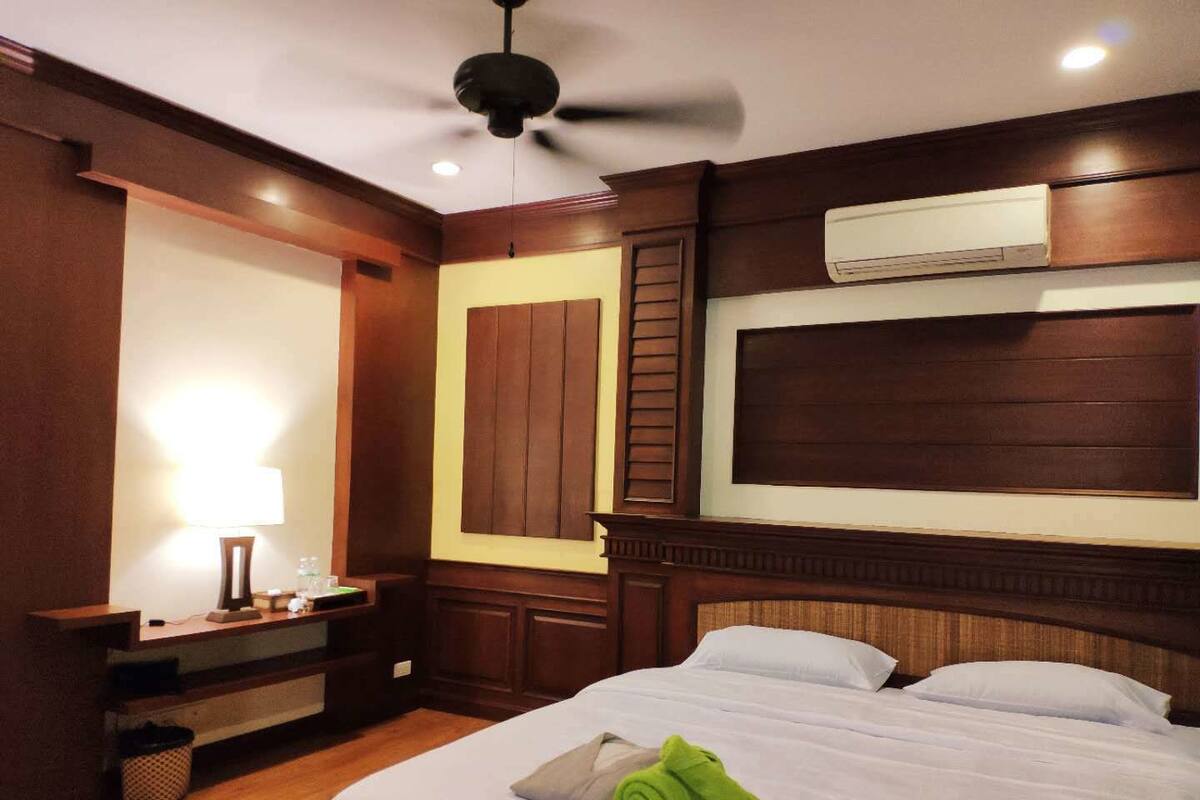 Une chambre d’hôtel avec un grand lit, un ventilateur de plafond, un téléviseur fixé au mur et un bureau avec une lampe.