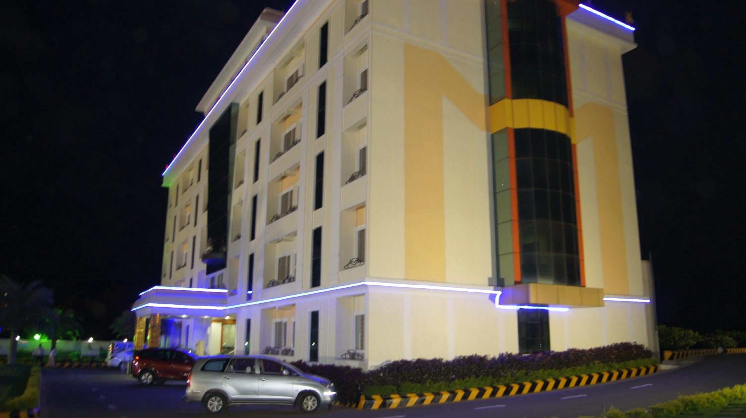 A multi-story hotel with a modern facade, featuring a prominent vertical stripe and illuminated entryways.