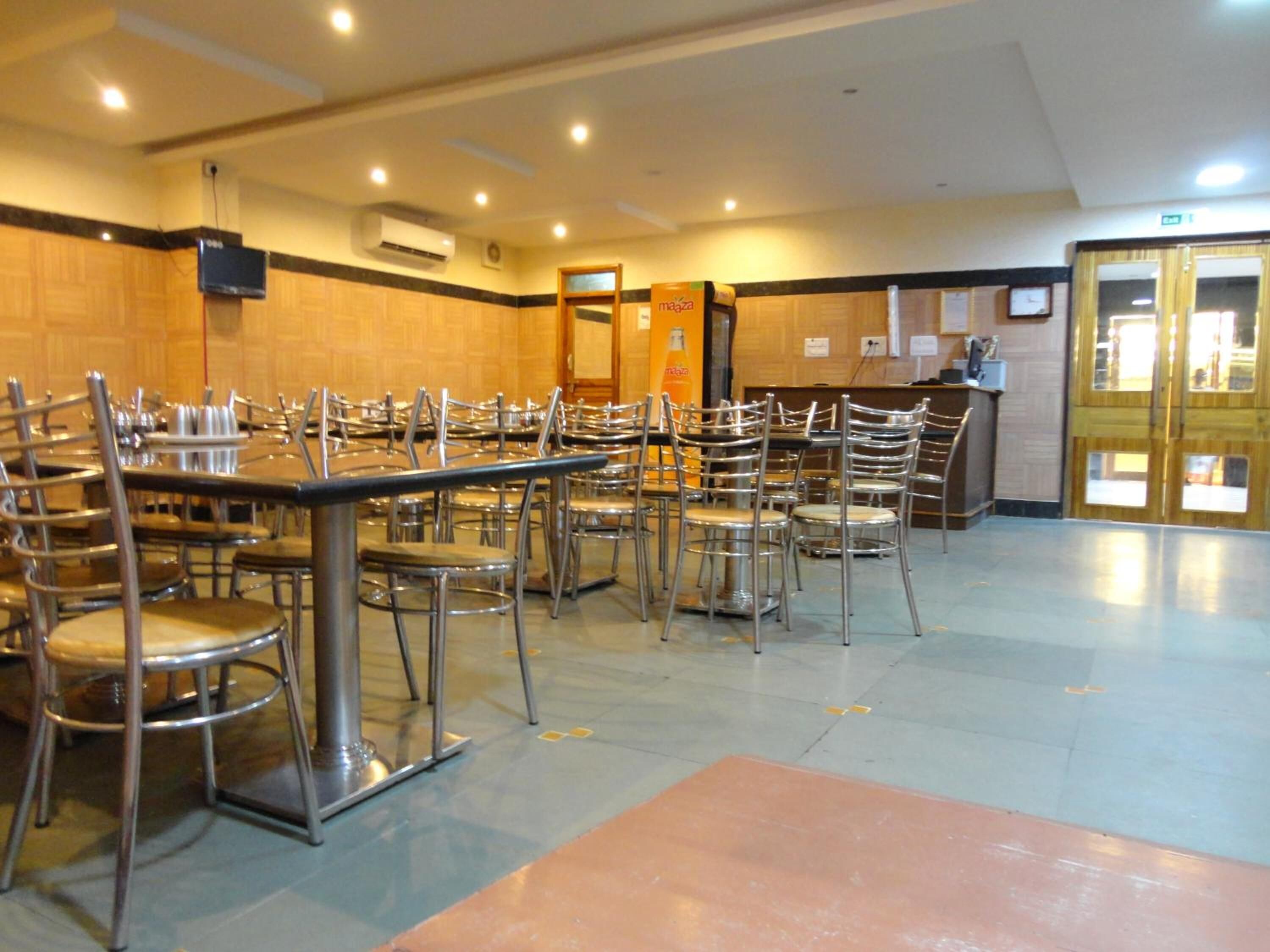 A spacious room with multiple tables and chairs, a reception desk, and a clock on the wall.