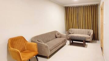 A living room with two sofas, a coffee table, and a single armchair.
