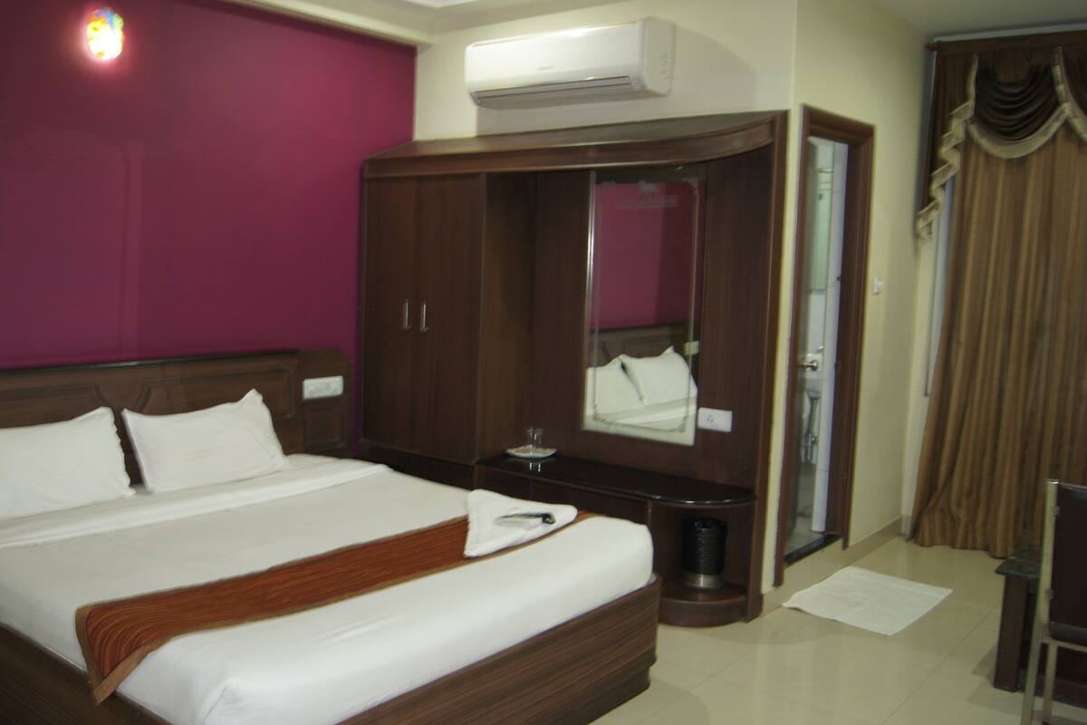 Une chambre d’hôtel avec un grand lit, une armoire, un miroir et un appareil de climatisation.