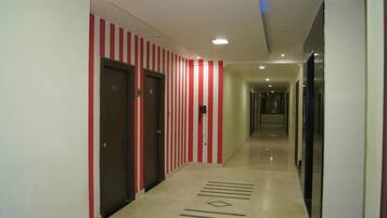 A hotel corridor with striped walls, doors, and a patterned floor.