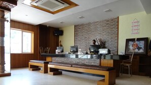A reception area with a stone wall, a wooden bench, and a counter with computers and a printer.