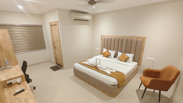 A modern hotel room with a large bed, a wooden desk, a chair, and a ceiling fan.