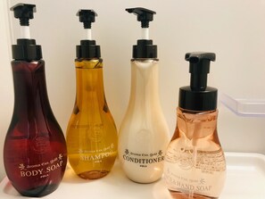 Cuatro botellas de productos para el cuidado corporal sobre una superficie blanca.
