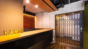 A reception desk with a wooden counter and a sign that reads "KAMON". - KAMON HOTEL Seto (Hiroshima)
