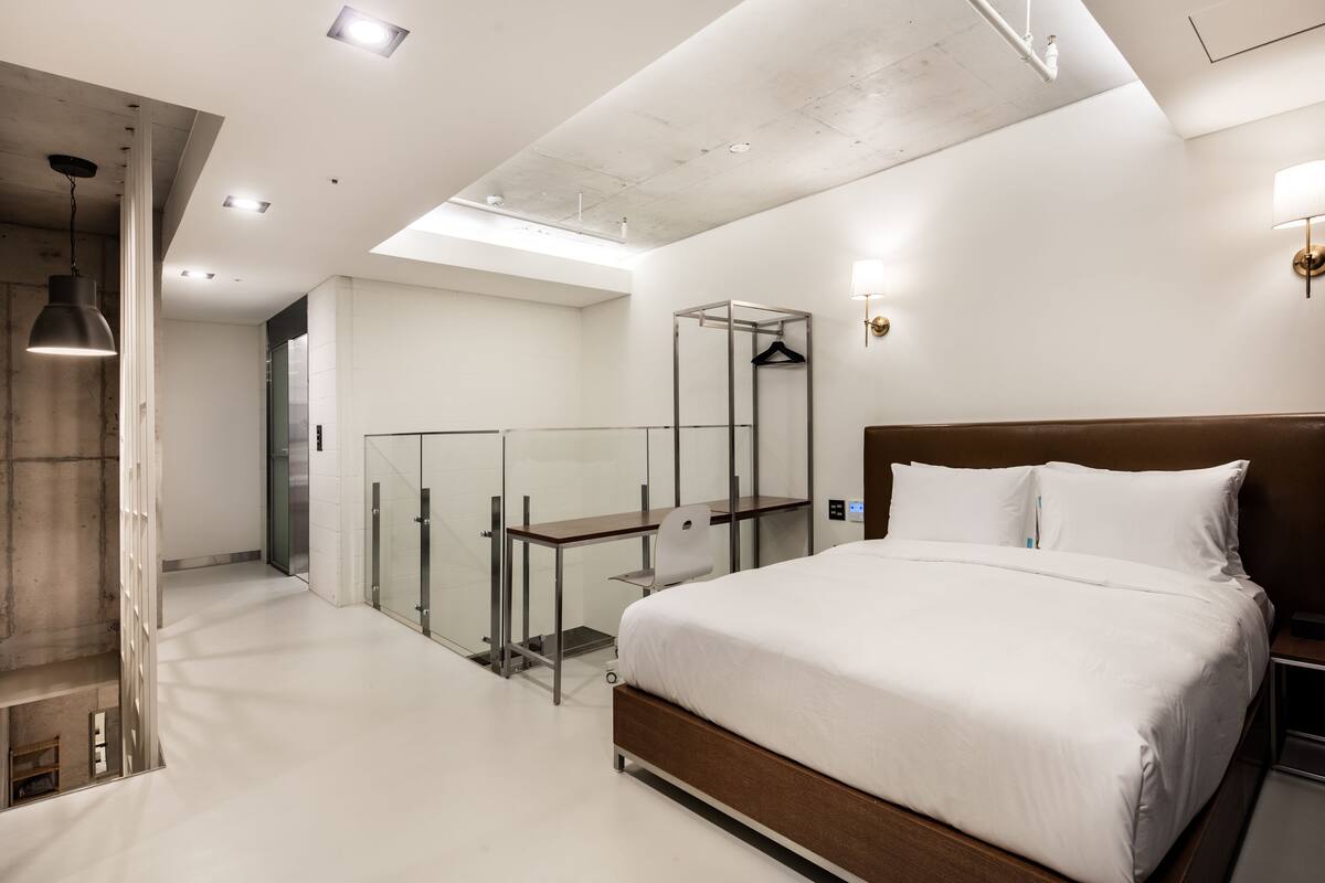 Une chambre d’hôtel moderne dotée d’un grand lit, d’un bureau et d’une cloison en verre.