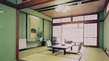 A traditional Japanese room with tatami flooring, a low table, a television, and a large window.