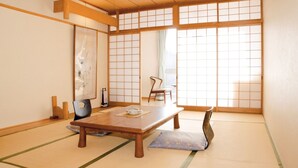 Una habitación japonesa tradicional con suelo de tatami, una mesa de madera baja y puertas correderas shoji.