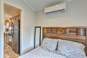 A bedroom with a wooden headboard, a bed with patterned bedding, and an air conditioning unit mounted on the wall.