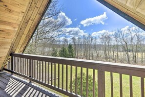 Un balcone in legno con vista su un prato e alberi.