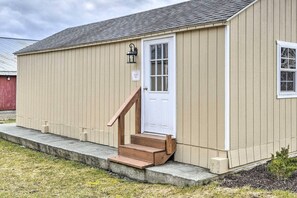 Un bâtiment d’un seul étage, avec une porte blanche et un petit escalier en bois menant à l’entrée.