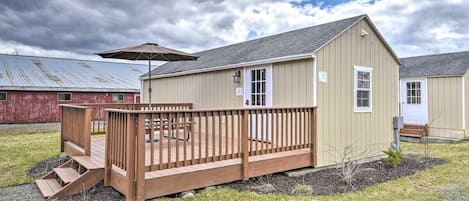 A single-story building with a wooden deck, a small porch, and a metal roof.