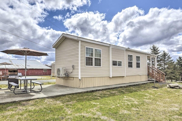 A single-story house with a covered patio area, a grill, and a picnic table.