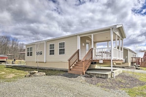 A single-story house with a covered porch and a staircase leading to the entrance. - Clydesdale Cottage · Luxury Poconos Stay Near NYC (Pleasant Mount)