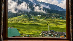 A view of a green valley with houses and a mountain in the background. - Pine View Resort - Gulmarg (Baramula)