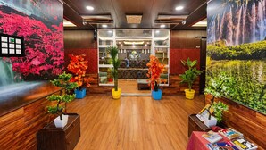 A hotel lobby with wooden floors, large floral murals, potted plants, and a reception desk. - Pine View Resort - Gulmarg (Baramula)