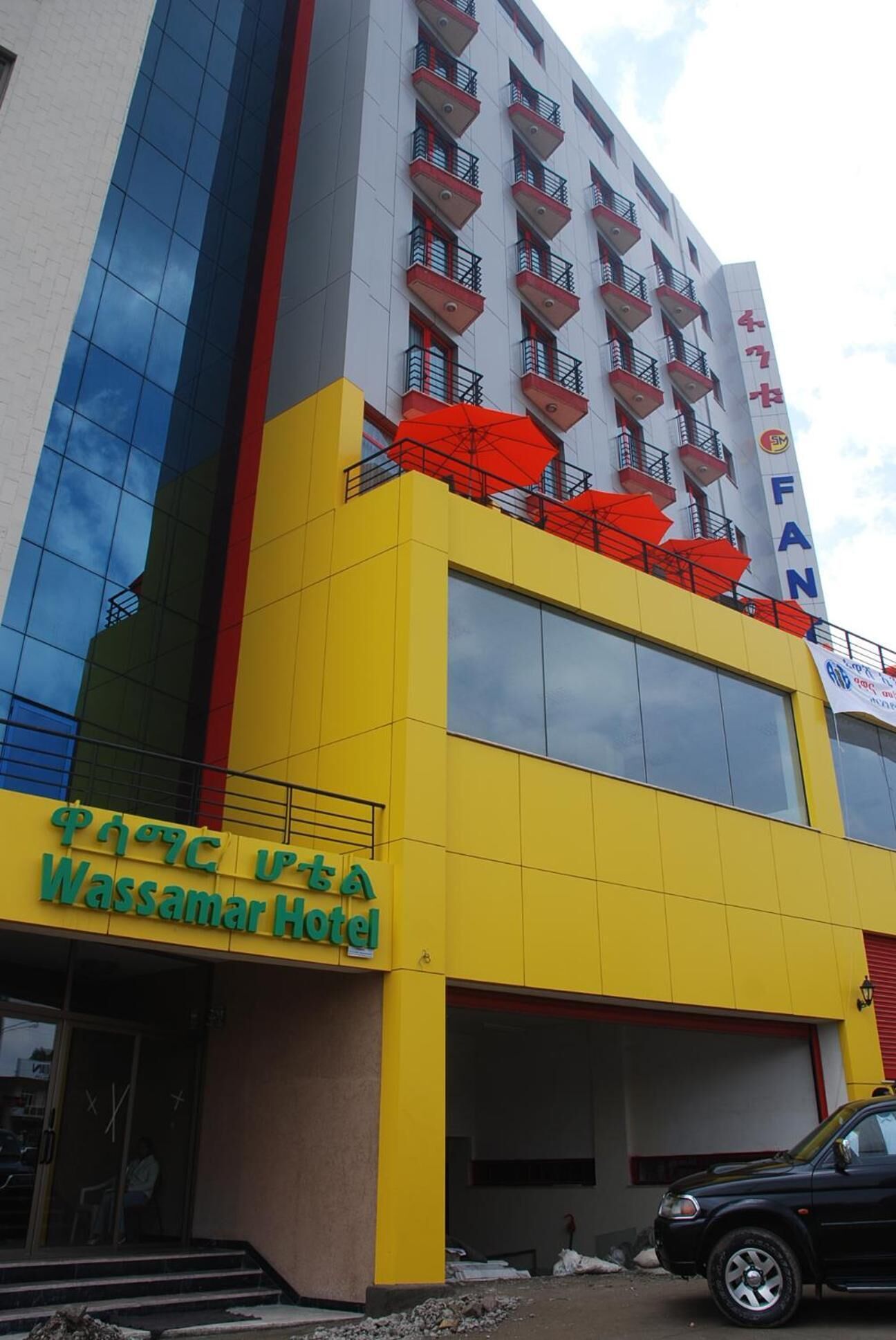 A hotel with a yellow facade, balconies with red railings, and a sign for the Wassamar Hotel.