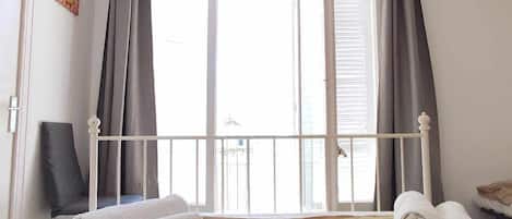Un dormitorio con cama, cortinas, una silla y una ventana.