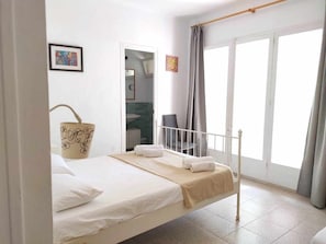Ein Schlafzimmer mit Bett, Bad und Blick ins Freie.