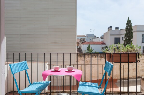 A balcony with two blue chairs and a table with pink tablecloth, overlooking a cityscape. - Beach 2 Large Balcones Quiet Rooms, Wifi, good views (Sitges)