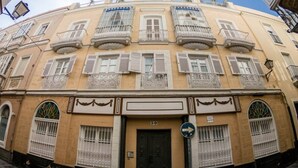 Un edificio con entrada central, varios balcones y una señal de tráfico que indica un giro a la derecha.