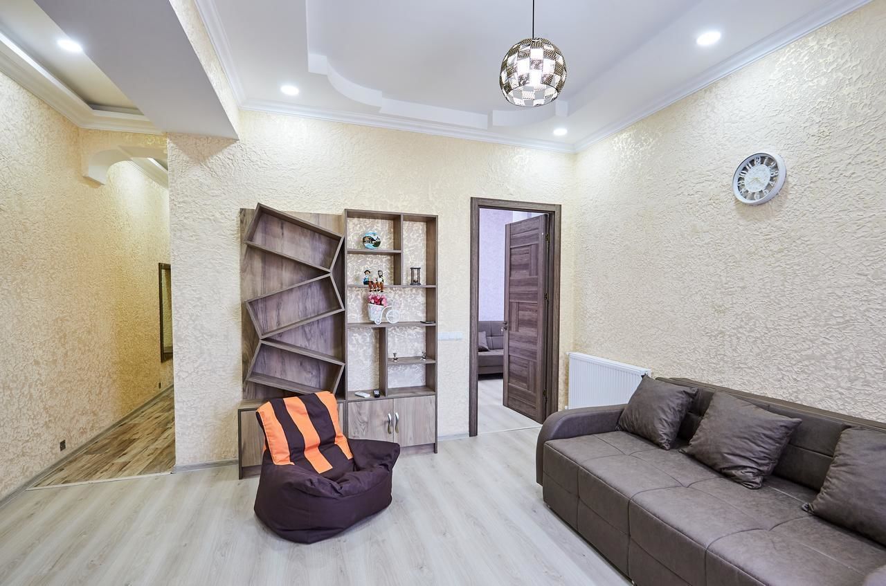 A modern living room with a sofa, a bean bag, and a built-in shelving unit.