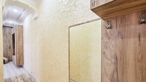 A hallway with wooden flooring, textured walls, and wooden cabinets. - Flat 013 (Tbilisi)