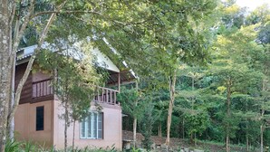 A rustic building with a balcony, surrounded by dense greenery and trees. - Farmstay at Pha Ma Chiangrai (Mae Chan)