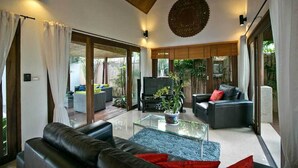 A modern living room with a glass coffee table, leather sofas, and a television.