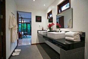 A modern bathroom with a black countertop, white sink, and a large mirror. There are towels stacked on the counter and a vase with flowers. - 2 Bedroom Pool Villa 4 min walk to beach SDV032-By Samui Dream Villas (Koh Samui)