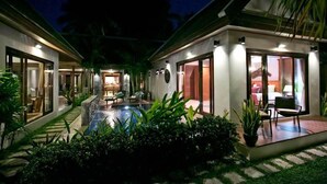 A modern hotel with a swimming pool, large windows, and a well-lit outdoor area.