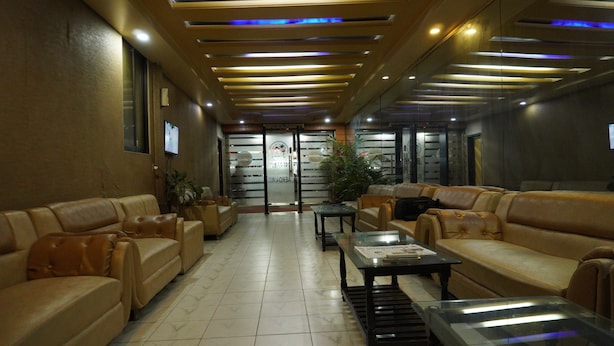 Um hall com sofás de couro, uma mesa de centro de vidro e um balcão de recepção.