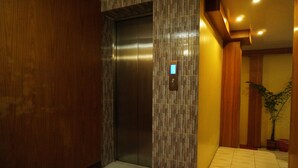 Um elevador com painel digital, parede de madeira e chão ladrilhado.
