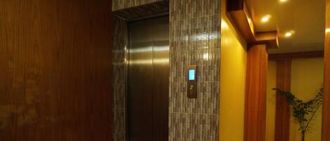 An elevator with a digital display, a wooden wall, and a tiled floor.