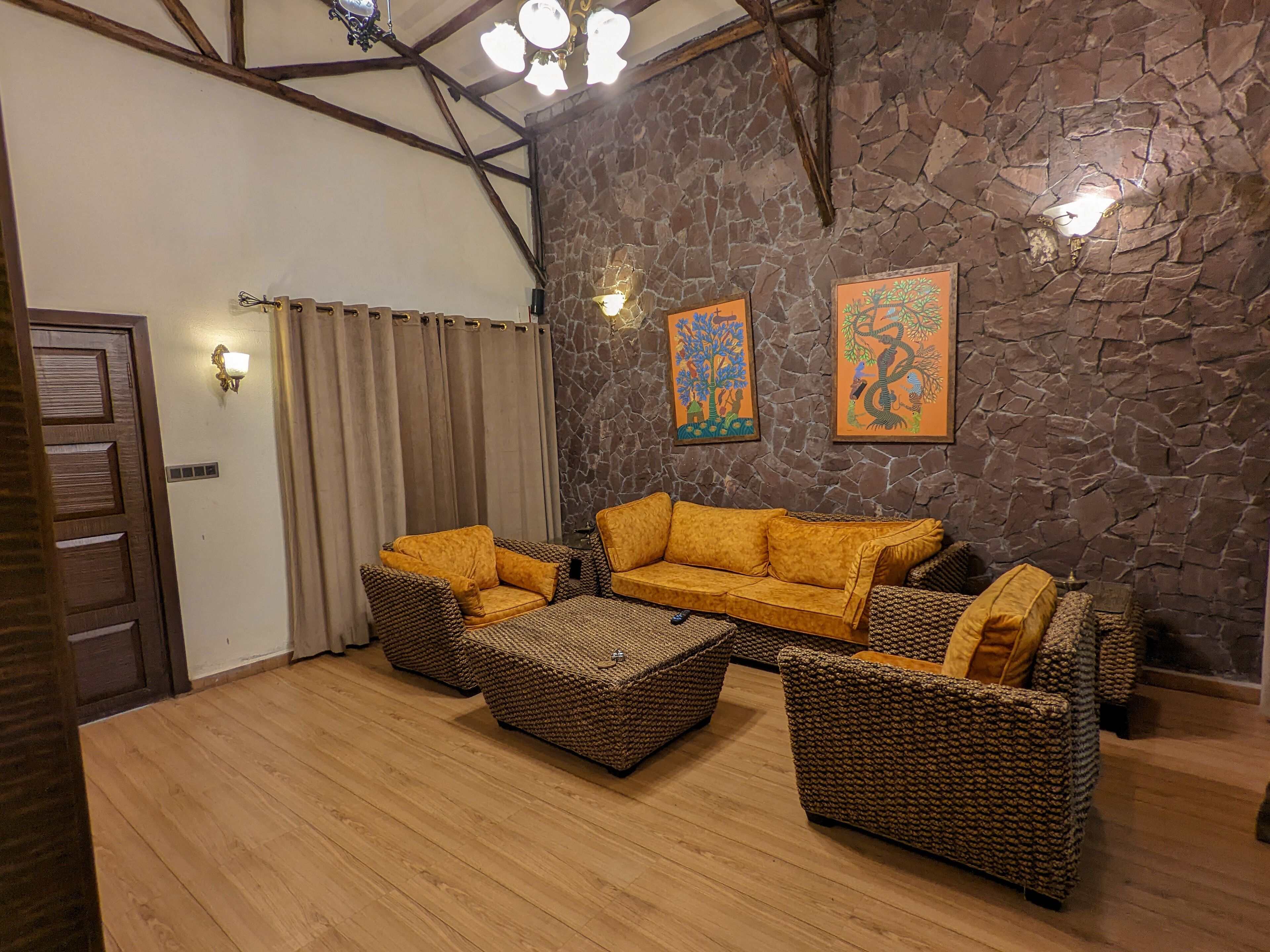 Una sala de estar acogedora con pared de piedra, techo de madera y un amplio sofá.