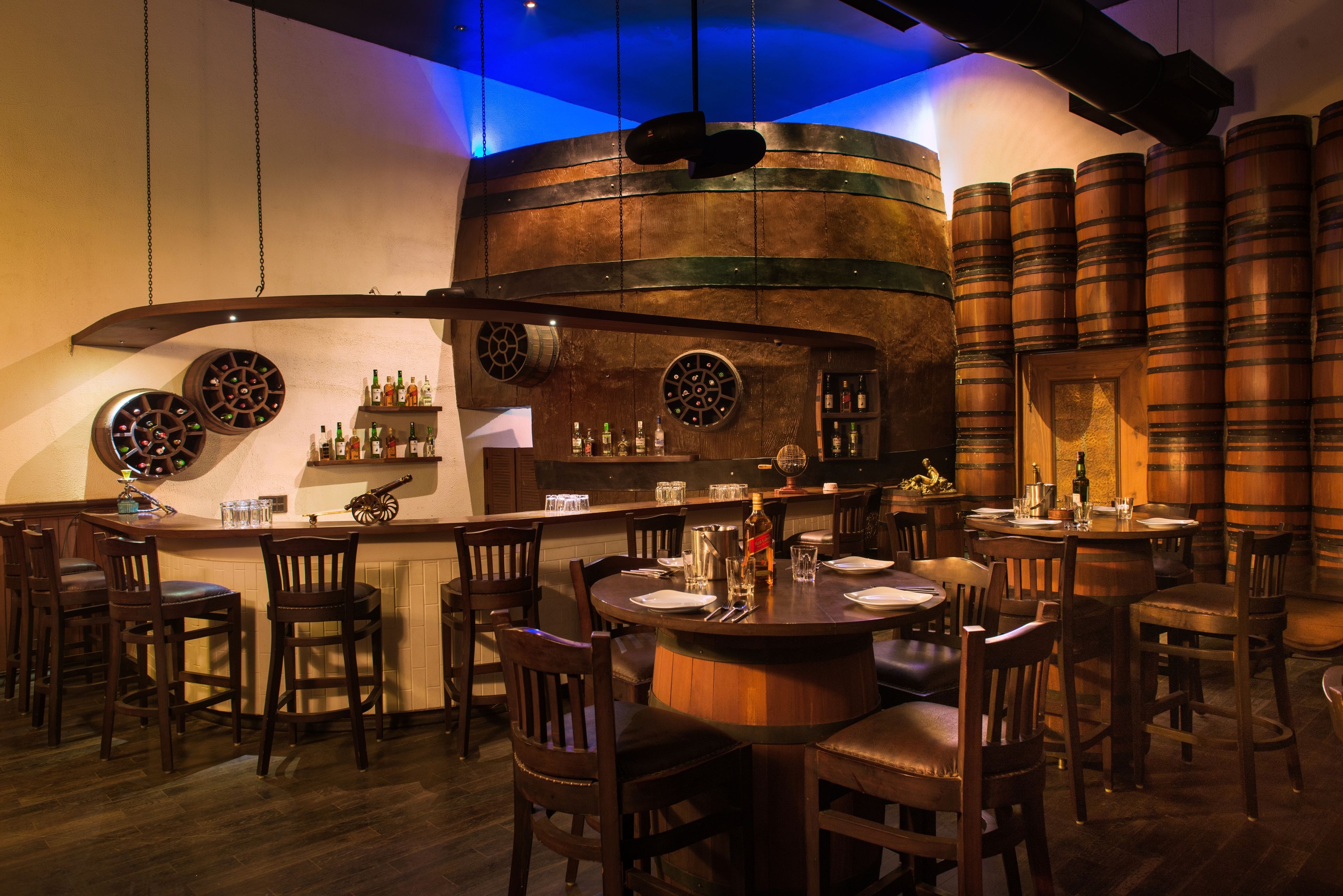 A bar area with wooden barrels, a bar counter, and multiple seating arrangements.