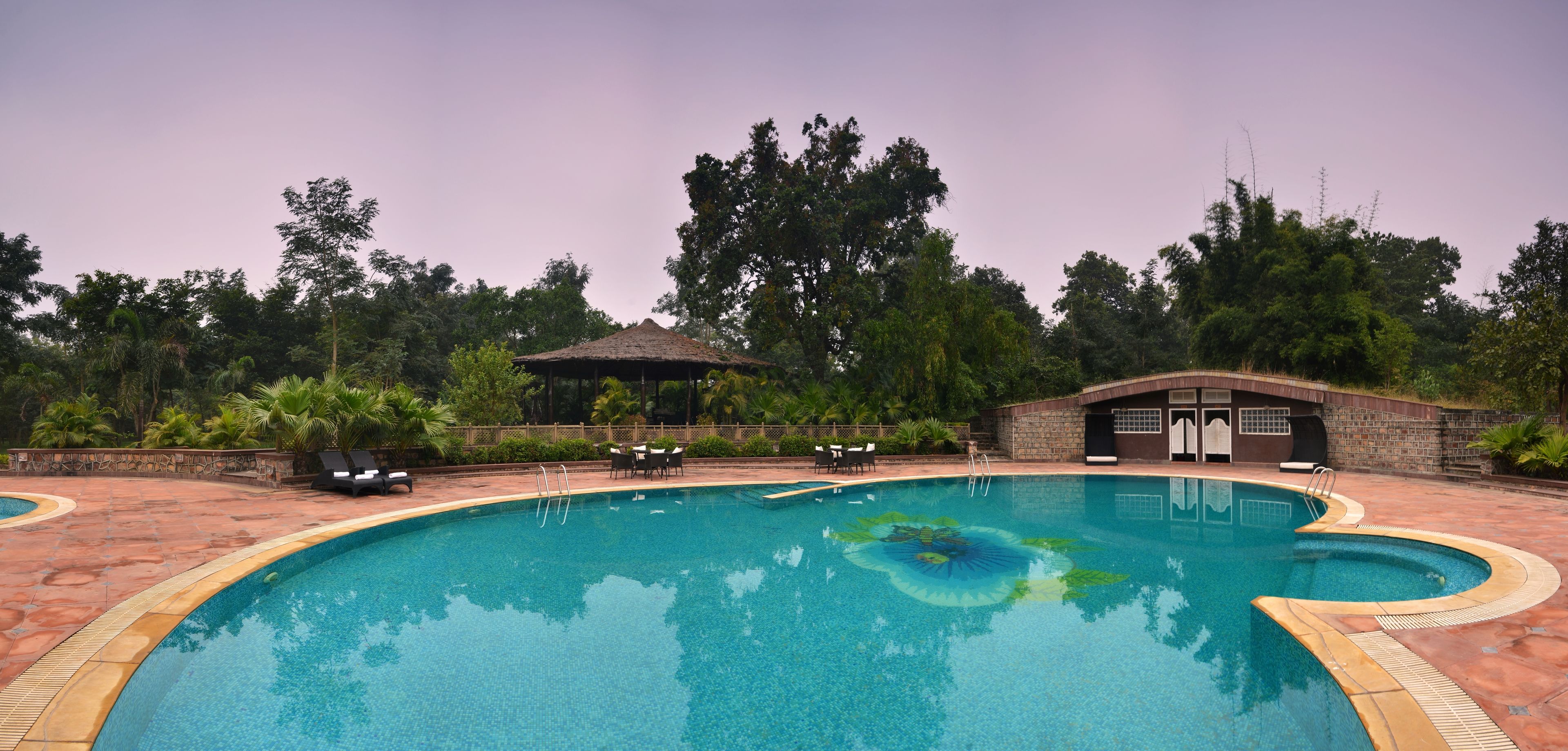 Piscina com espreguiçadeiras e um gazebo em área ajardinada.