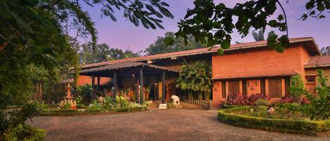 A traditional building with a tiled roof, surrounded by lush greenery and a cobblestone pathway.
