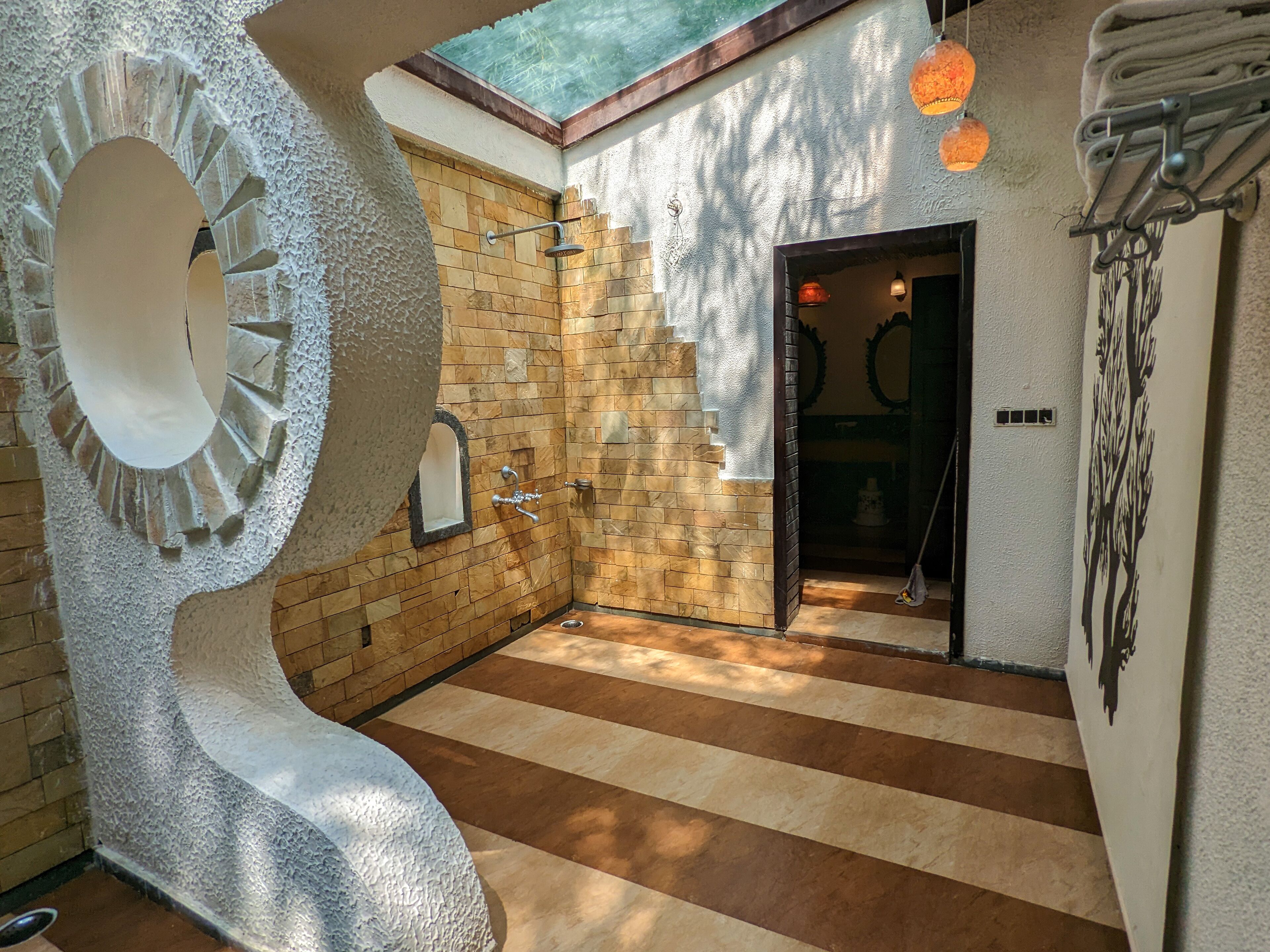 Une salle de bain avec un mur en pierre, une douche, un porte-serviettes et une vue sur l’extérieur.