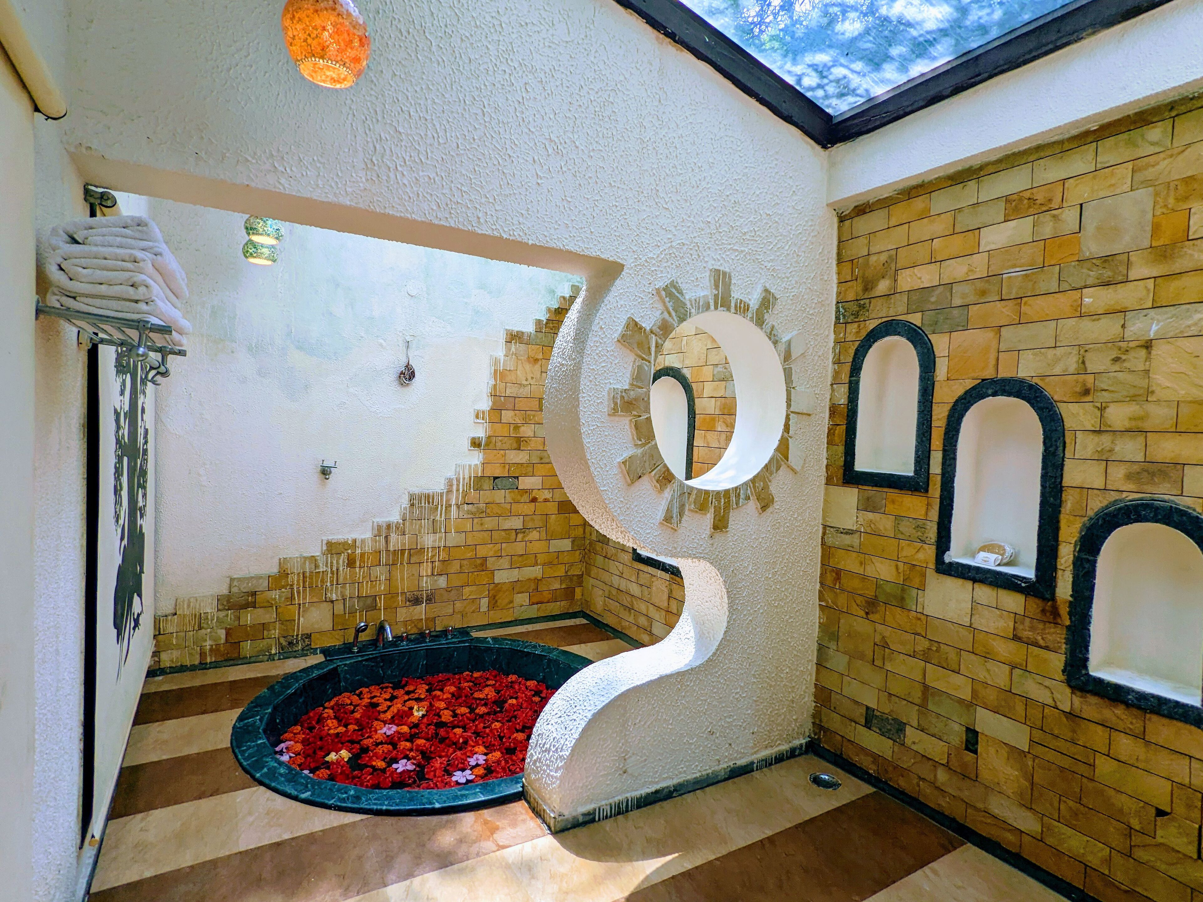 A bathroom with a tiled floor, a circular sink, and a shower area with red flowers.