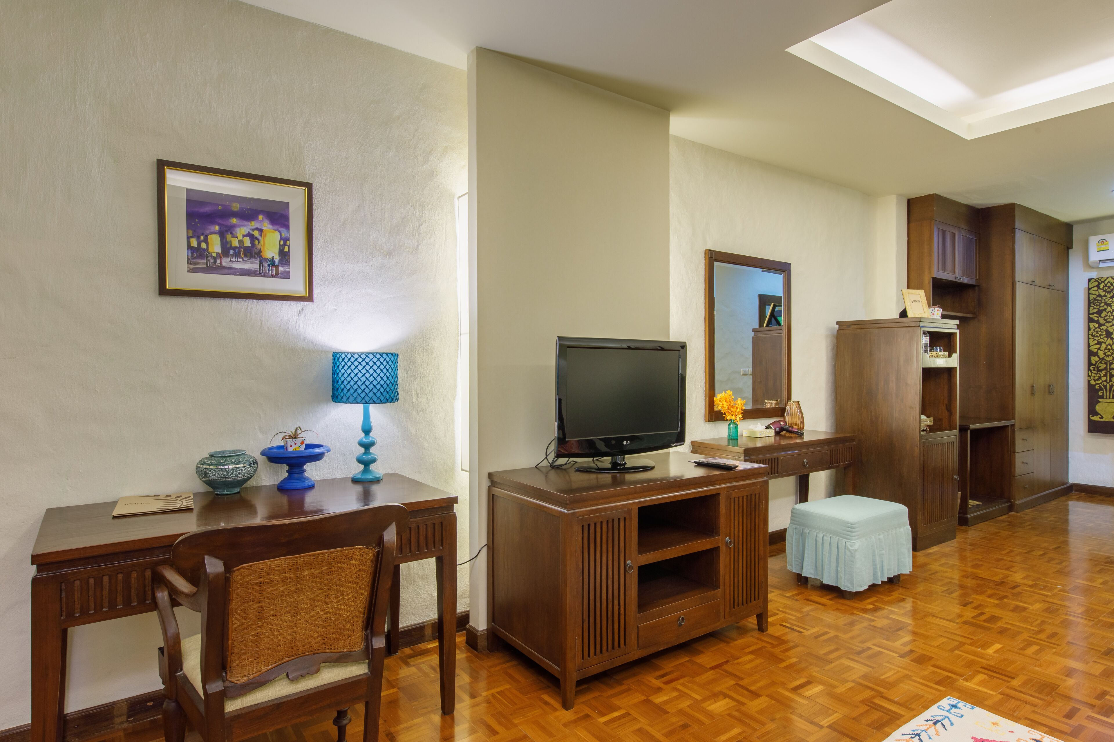 A living room with a wooden entertainment center, a television, a dining table with chairs, and a small stool.