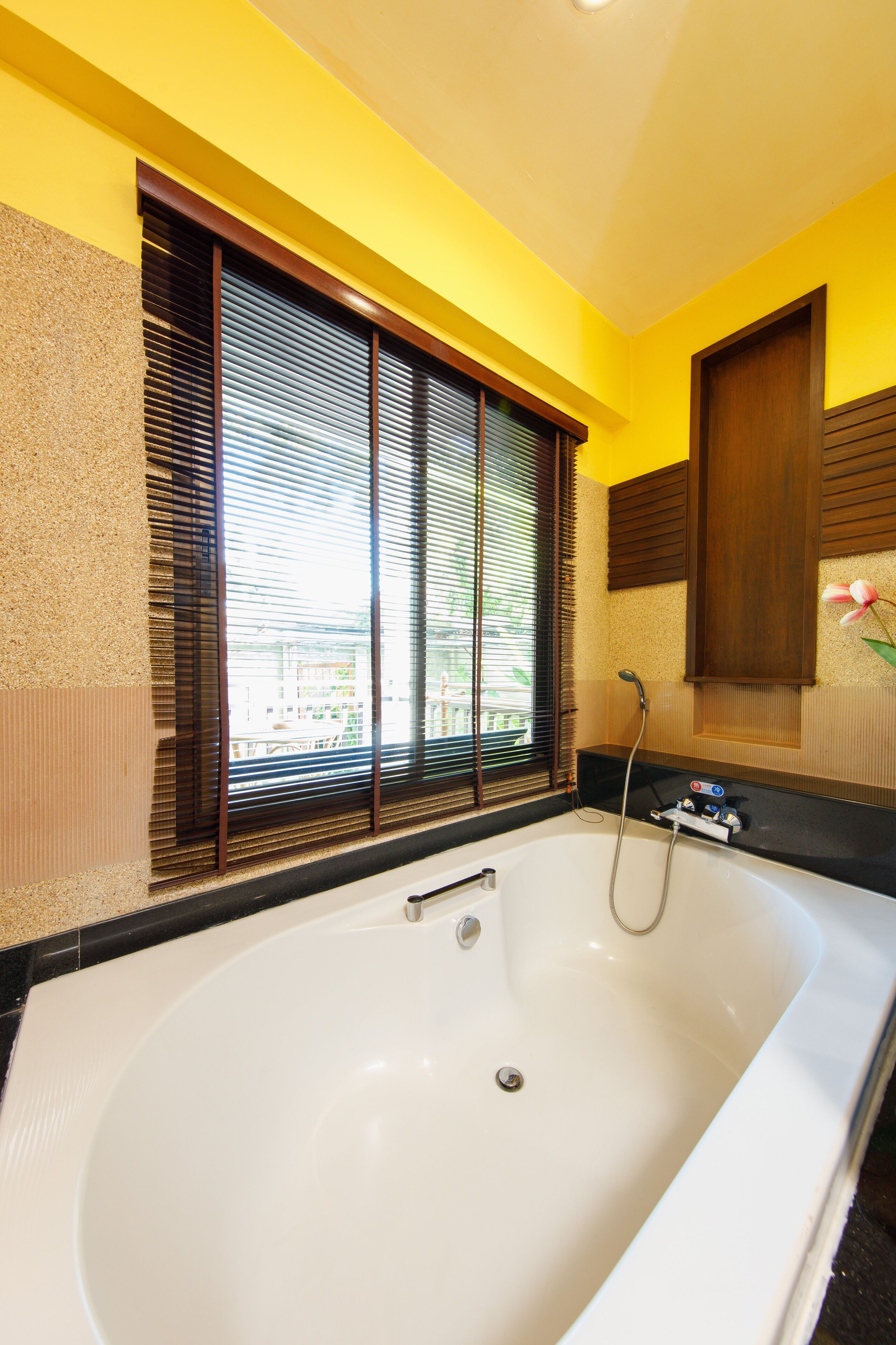 Un baño con una bañera grande, persianas de madera y una zona de ducha.