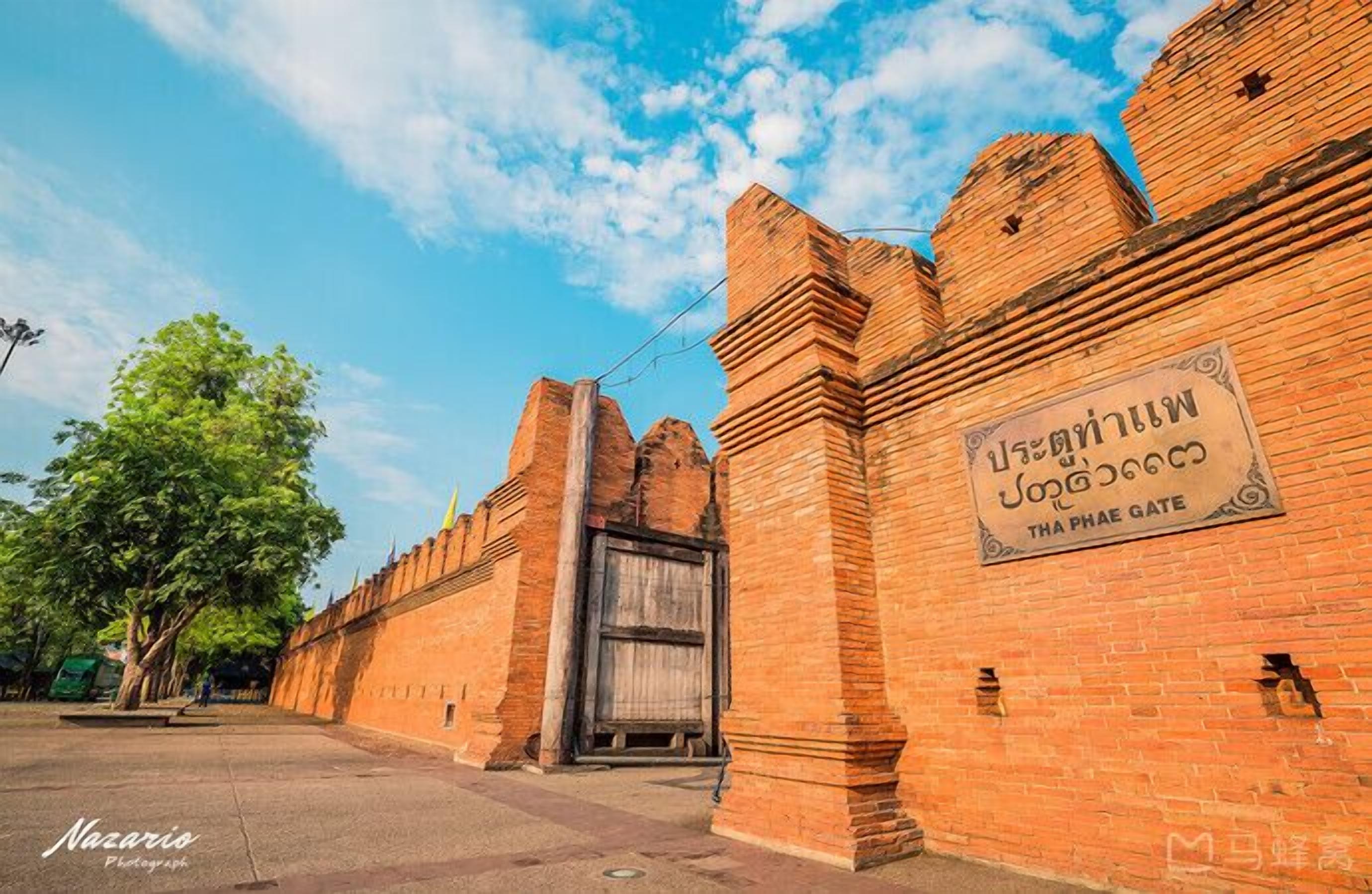 Un mur de briques historique sur lequel est apposée une plaque indiquant « Porte de Tha Phae ».
