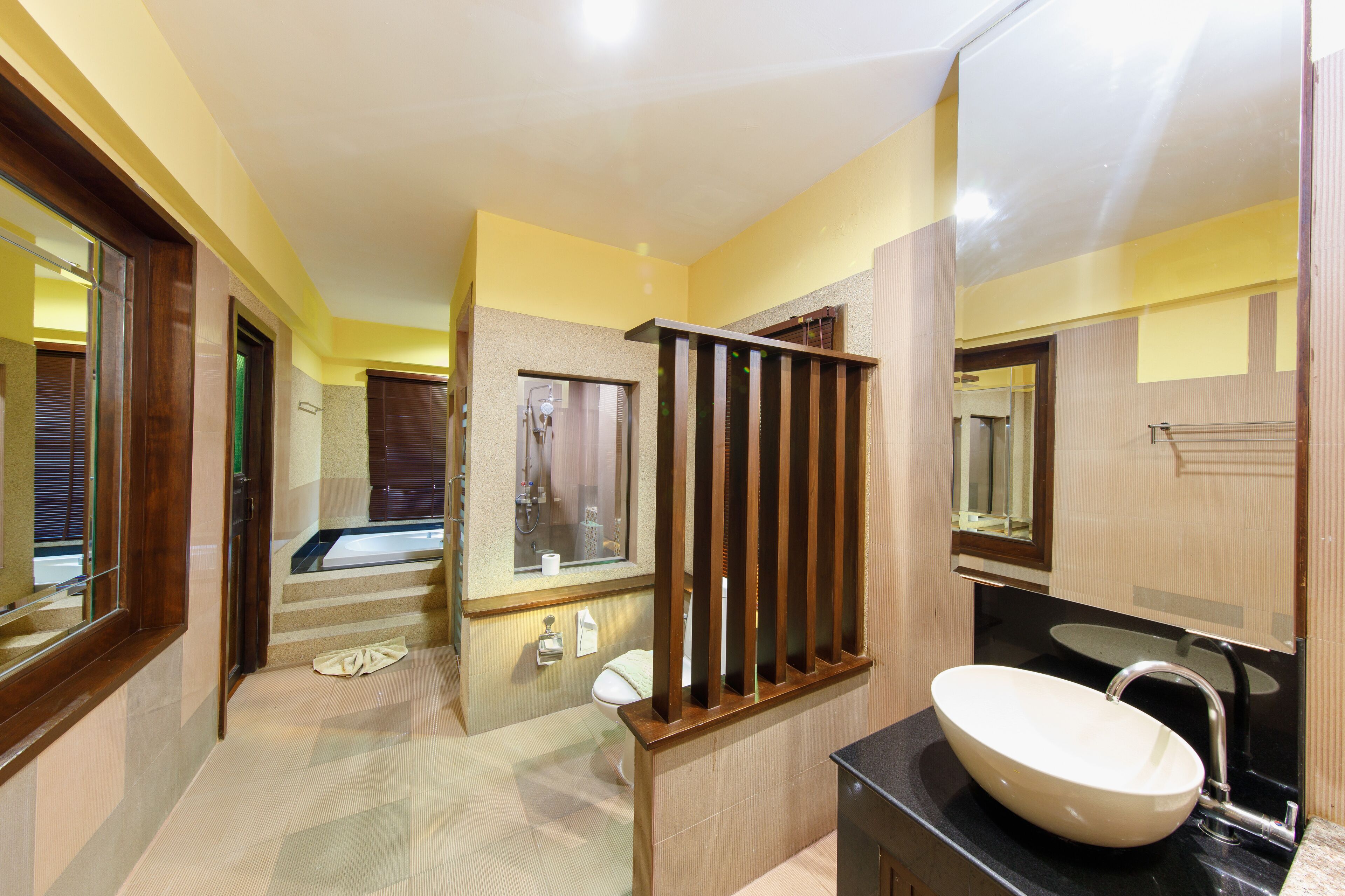 Un bany modern amb un mirall gran, un lavabo blanc i un vàter.
