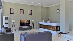 A modern hotel lobby with a reception desk, a large flat-screen TV, and a seating area with sofas. - Legend Business Hotel Batumi (Batumi)