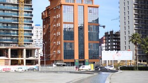 A modern hotel building with a glass facade, a visible sign for the Legend Business Hotel, and a reflection in a water feature. - Legend Business Hotel Batumi (Batumi)